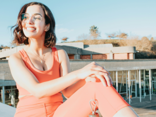 woman in sports wear sitting in the edge of a bridge